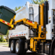 Side load cart tipper lifting a wheeled waste container into a garbage truck